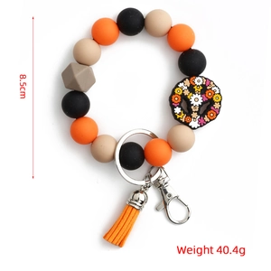 Détail du porte-clés en perles silicone avec signe de paix fleuri et pompon orange