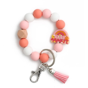 Détail du porte-clés bracelet en perles de silicone avec breloque arc-en-ciel et pompon rose