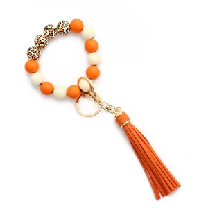 Détail d'un porte-clés bracelet perlé avec pompons oranges et perles en silicone léopard