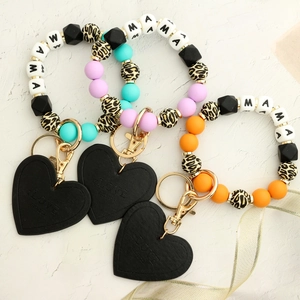 Close-up of three leopard print silicone bead keychains with heart charm and MAMA letters