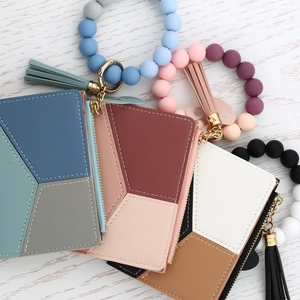Three geometric mini wallets with silicone bead wristbands and tassels on wood background