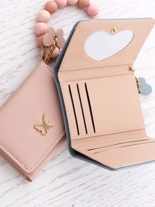 Detail of mauve leather tri-fold wallet with butterfly metal clasp and beaded wristlet