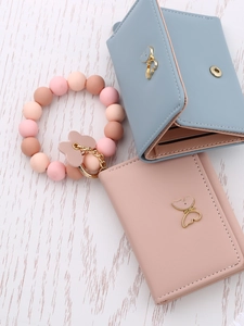 Flat lay of pink and blue faux leather wallets with gold butterfly and silicone bead bracelet
