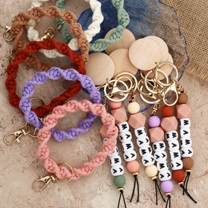 Detail of colorful braided keychain with wood beads and MAMA letter charms on stone surface