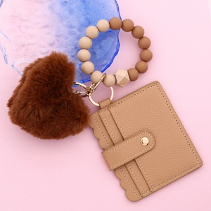 Détail du bracelet en perles silicone avec cœur en peluche et porte-cartes en cuir ondulé