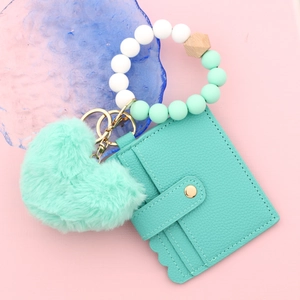 Détail du portefeuille en cuir vert menthe avec cœur en peluche et porte-clés en perles