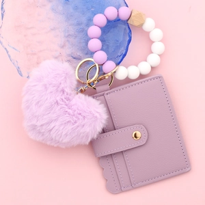 Détail du bracelet en perles de silicone violettes avec porte-cartes en cuir et pompon