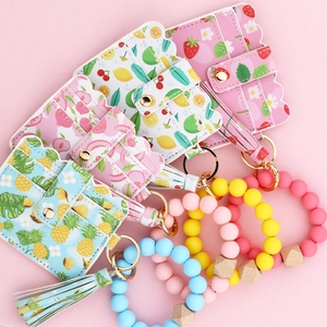 Detail of printed zipper wallet and silicone beaded keychain bracelet with leather tassel