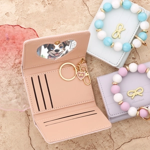 Close-up of small bowknot folding wallet with heart photo slot and beaded bracelet