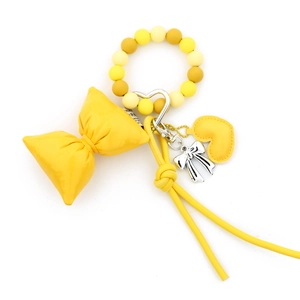 Yellow silicone bead bracelet keychain with a large leather bow and heart charm