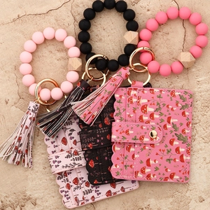 Detailed flat lay of three sets with silicone bead bracelets, floral PU cardholders and tassels