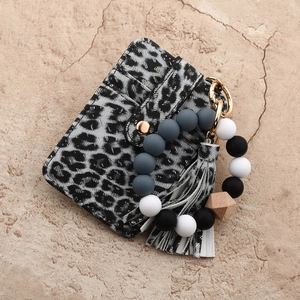 Macro shot of leopard print card holder with silicone bead bracelet and gold hardware