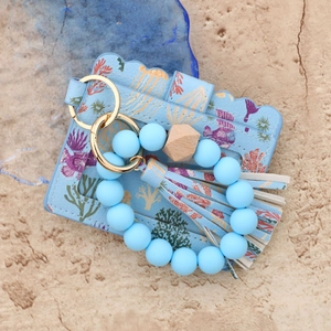 Detail of coral print card holder with blue silicone bead wristlet and tassel keychain