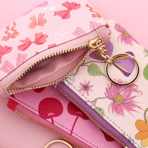 Close-up of printed PU leather wallets with bow, floral patterns and gold metal rings
