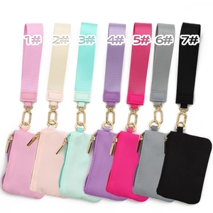 Detail of seven mini nylon coin purses with wrist straps and golden metal carabiners