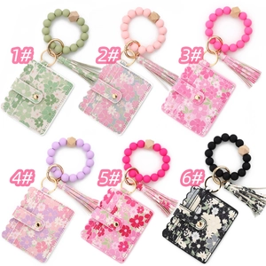 Dettaglio di portacarte floreali con braccialetti in perline di silicone e nappe