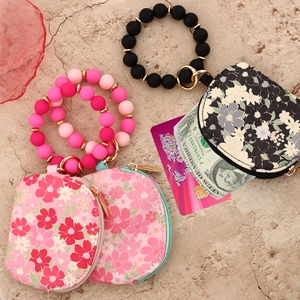 Detail of floral printed wallet with pink silicone beaded bracelet and metal key ring