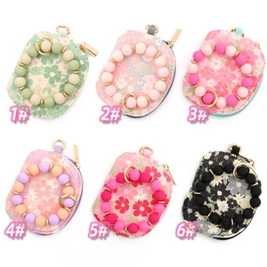 Detailed display of six floral printed wristlet wallets with beaded bracelets and gold zippers