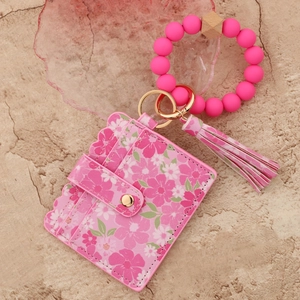 Dettaglio porta carte floreale con bracciale in silicone rosa e portachiavi dorato
