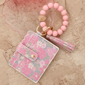 Detail view of pink floral card holder with silicone bead bracelet and tassel keychain