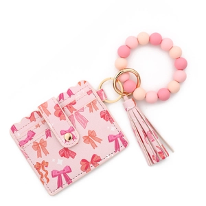 Close-up of pink PU leather card holder with bow patterns and silicone bead bracelet