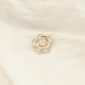 Detail of camellia brooch with golden outlines and shimmering rhinestones on white petals