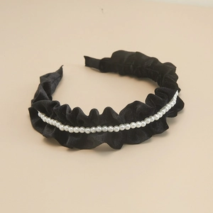 Detailed macro view of black pleated velvet headband with white pearl embellishments