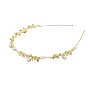 Détail d'un serre-tête doré orné de pierres œil-de-chat, de perles et de strass brillants