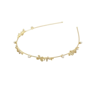 Détail d'un serre-tête doré orné de perles blanches élégantes et de trèfles