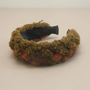 Detail of bohemian thick braided headband in olive, yellow, and red yarn texture
