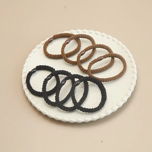 Close-up of 8 pieces of elastic twisted hair ties in black and brown on a white tray