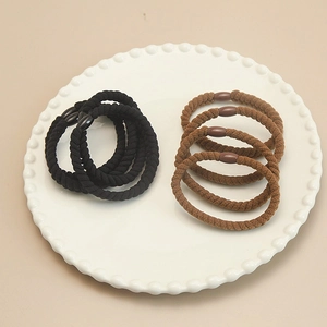 Elastic braided hair ties set in black and brown colors on white decorative plate