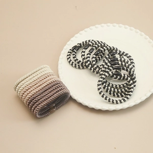Detail showing hand-woven elastic hair ties with gradient warm tones and black beads