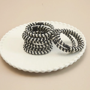 Elastic black and white striped spiral hair ties set on a white ceramic plate