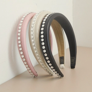 Detail view of handmade leather headbands with rhinestones in pink, beige, and black