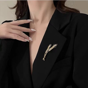 Detailed view of elegant golden wheat brooch with pavé zircons on black blazer
