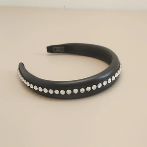 Detailed macro view of black leather padded headband with shimmering rhinestone row inlay
