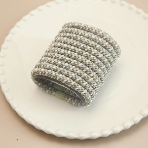 Detailed close-up of handmade woven elastic hair ties in soft Morandi colors on a tray