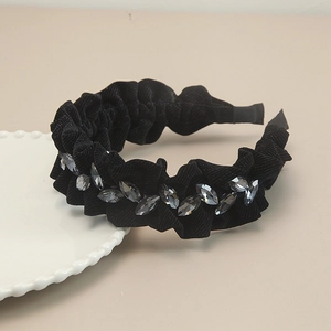 Close-up of black pleated velvet headband with grey marquise rhinestones on a table