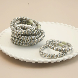 Handmade high-elasticity braided hair ties in Morandi tones on a white ceramic plate
