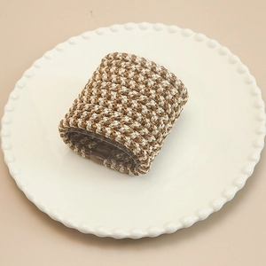 Close-up of hand-woven high elastic hair scrunchies in brown and beige on a ceramic plate