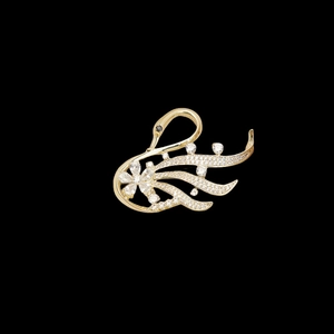 Close-up of golden swan brooch with sparkling zircons and flower detail on black surface