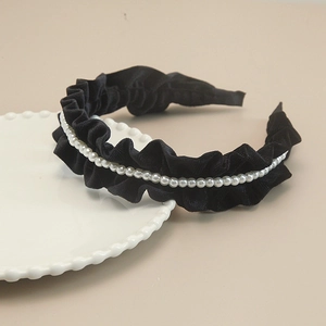Close-up of black velvet headband with elegant white pearl beads and ruffled texture