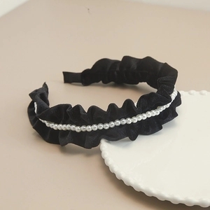 Close-up of black velvet headband with elegant pearls and textured ruffle design