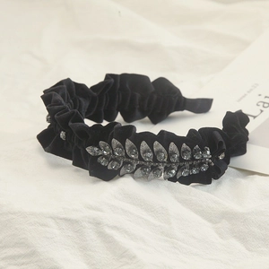 Detailed shot of black velvet pleated headband with grey rhinestone leaf ornament