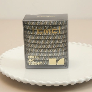 Detail of multi-colored braided elastic hair bands in a transparent luxury gift box