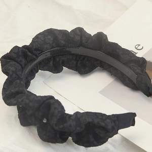 Detailed macro view of black textured satin headband with pleated design and rhinestone