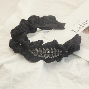 Macro shot of black pleated fabric headband with glittering silver leaf rhinestones