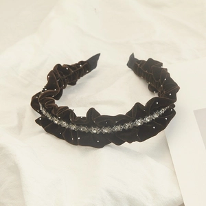 Close-up of velvet headband with sparkling rhinestones and elegant pleated ruffles