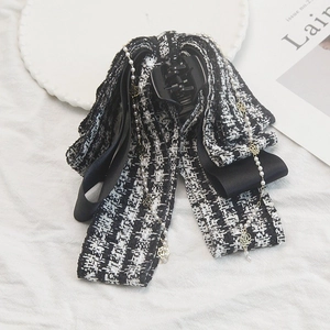 Close-up of tweed bow hair claw clip with pearl and golden rose chain tassels
